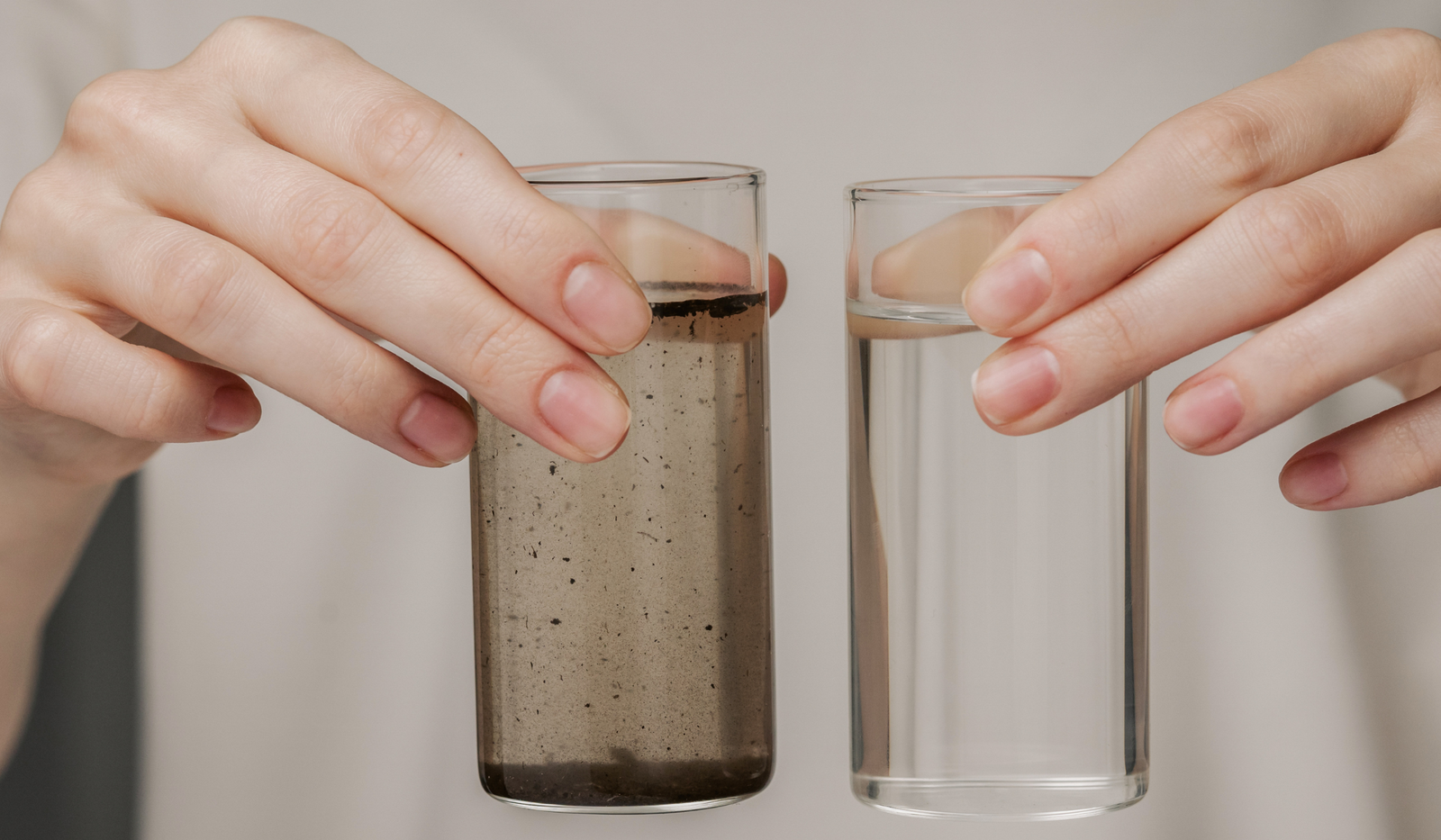 Dos vasos de agua, una limpia y otra contaminada, , ilustrando el riesgo de contaminación por nitratos del agua de consumo